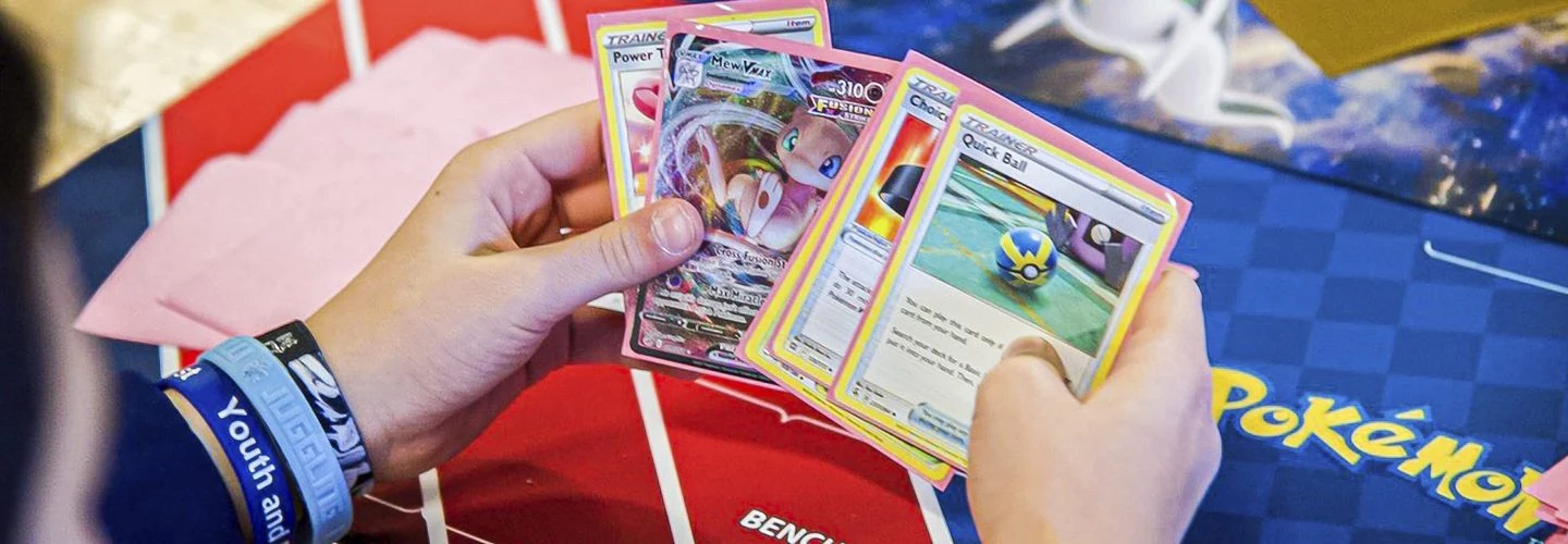 Hands holding Pokémon cards during a tabletop match, from the official Play! Pokémon rules site.